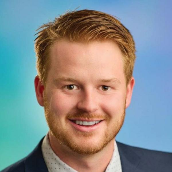 Headshot of smiling male student with orange-blond, short hair and a short mustache and beard.
